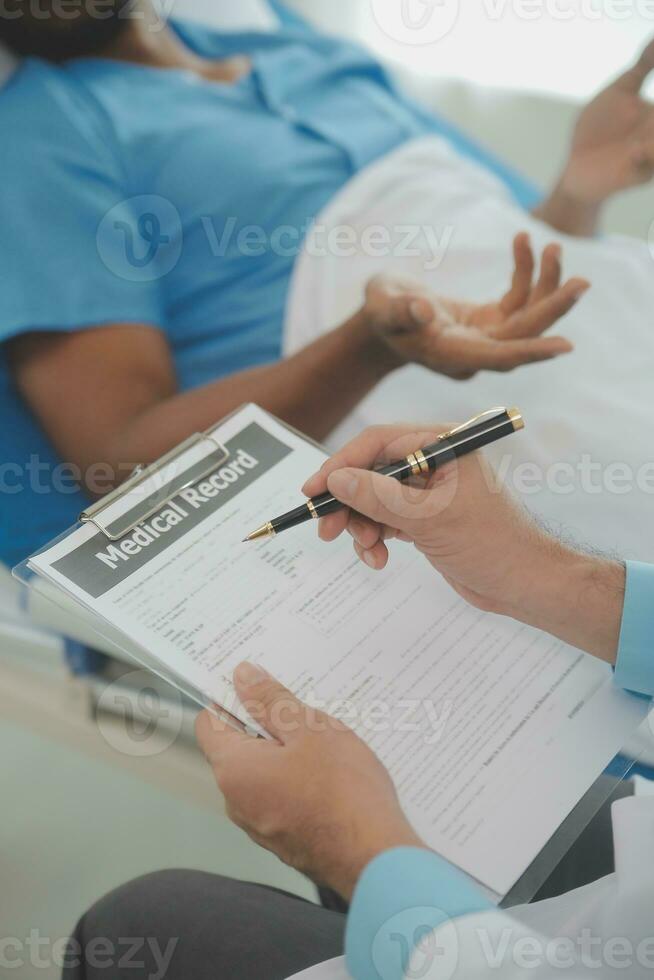 Close up of doctor sitting on bedside of male patient in hospital photo