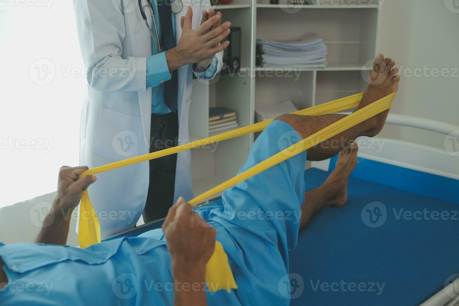 Male patient using elastic band while doing physical exercises for leg muscles at modern clinic, rehabilitation center or hospital. Close up of man's foot. Physiotherapy concept photo
