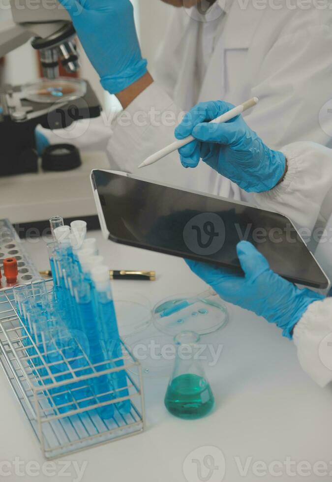 Health care researchers working in life science laboratory. Young female research scientist and senior male supervisor preparing and analyzing microscope slides in research lab. photo