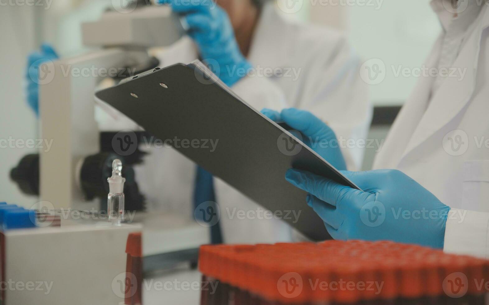 Health care researchers working in life science laboratory. Young female research scientist and senior male supervisor preparing and analyzing microscope slides in research lab. photo