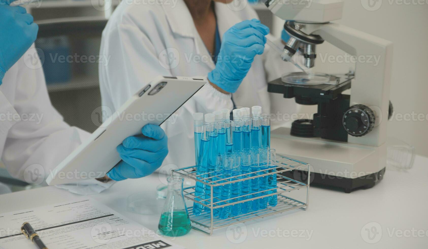 Health care researchers working in life science laboratory. Young female research scientist and senior male supervisor preparing and analyzing microscope slides in research lab. photo