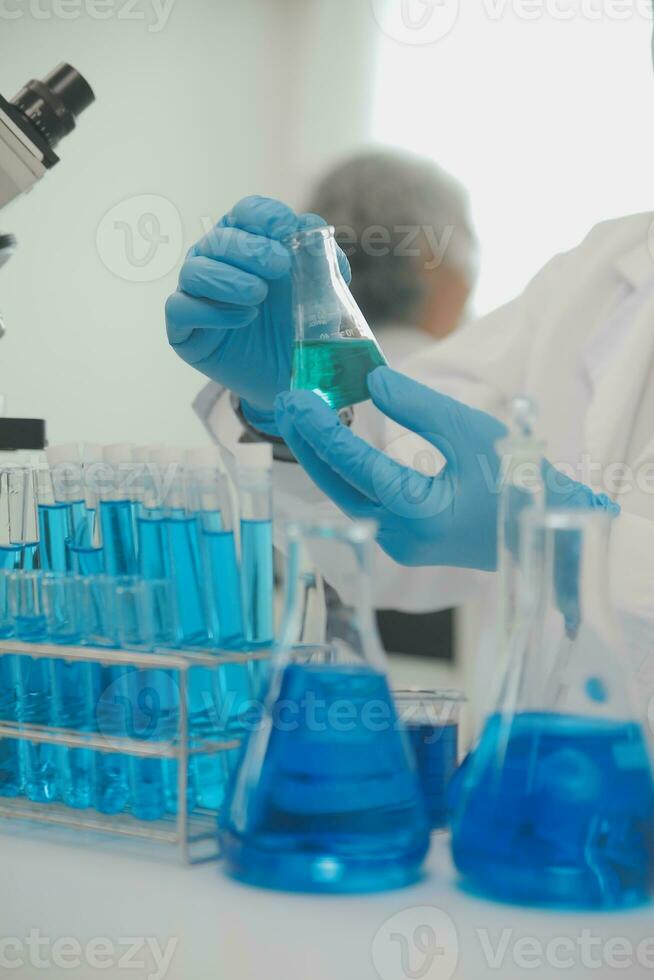 Health care researchers working in life science laboratory. Young female research scientist and senior male supervisor preparing and analyzing microscope slides in research lab. photo
