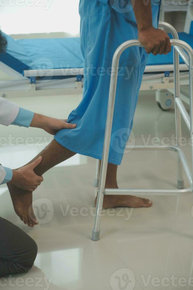young asian physical therapist working with senior woman on walking with a walker photo