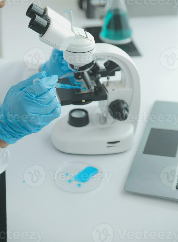 Health care researchers working in life science laboratory. Young female research scientist and senior male supervisor preparing and analyzing microscope slides in research lab. photo