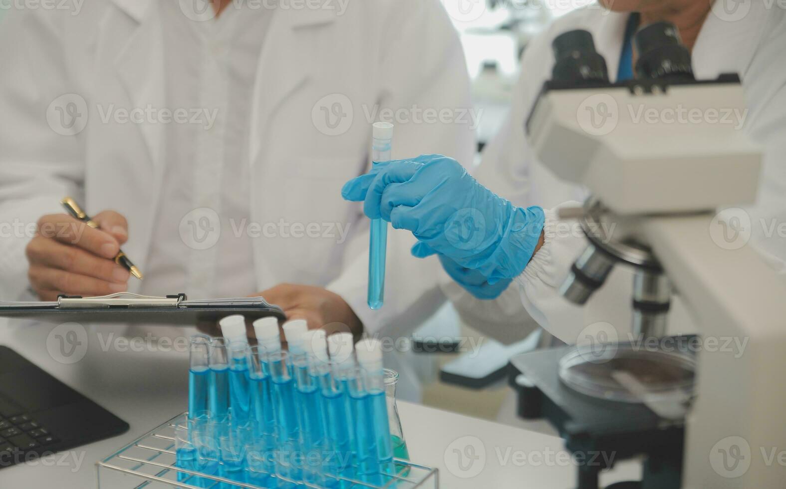 Health care researchers working in life science laboratory. Young female research scientist and senior male supervisor preparing and analyzing microscope slides in research lab. photo