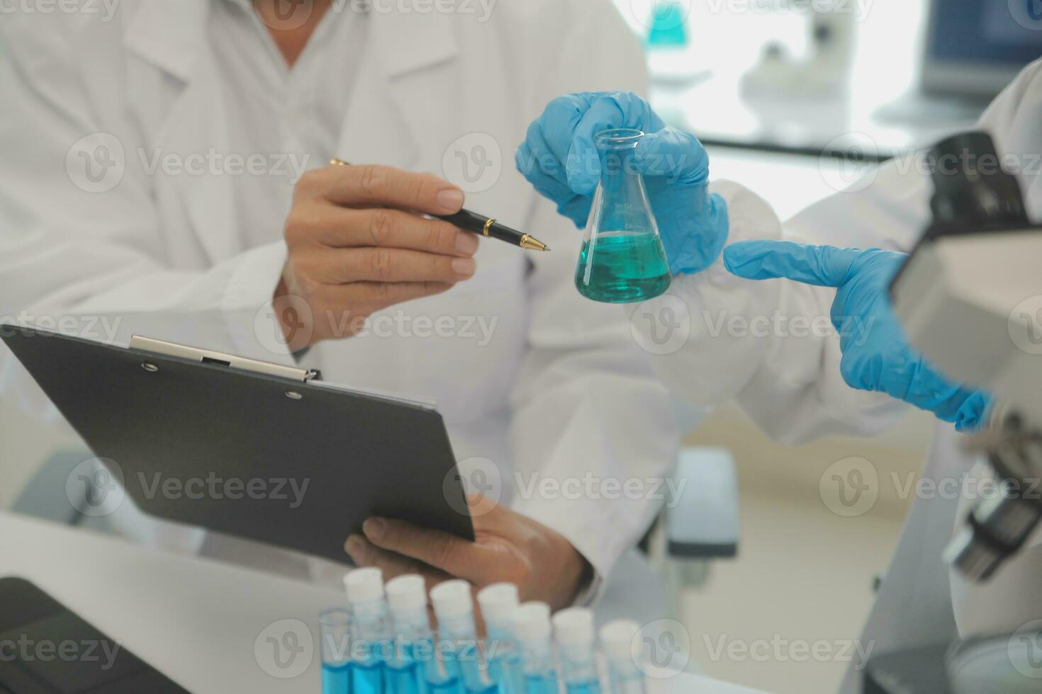 Health care researchers working in life science laboratory. Young female research scientist and senior male supervisor preparing and analyzing microscope slides in research lab. photo