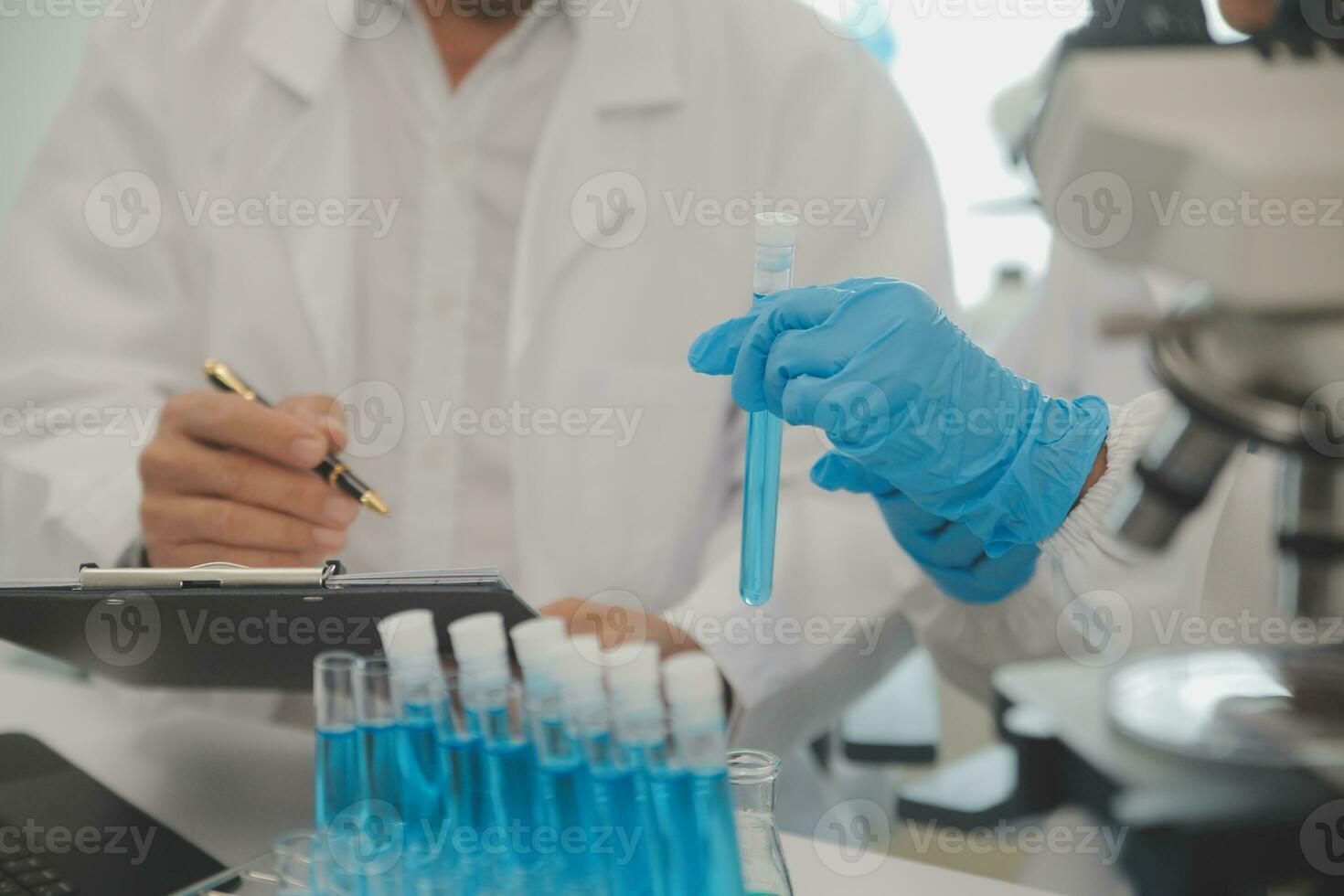 Health care researchers working in life science laboratory. Young female research scientist and senior male supervisor preparing and analyzing microscope slides in research lab. photo