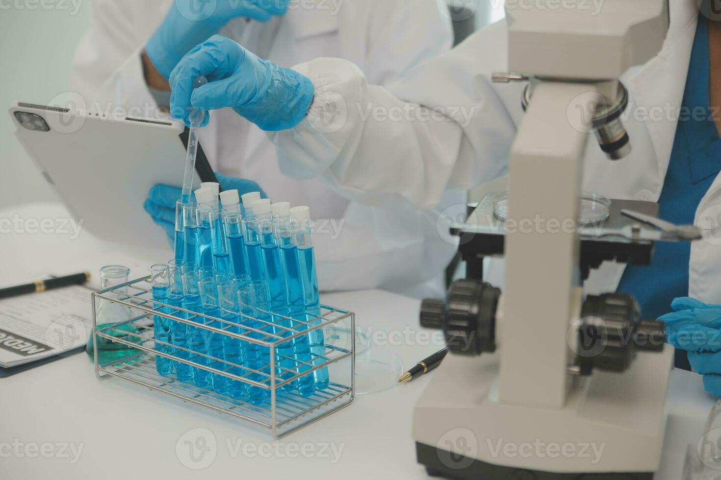 Health care researchers working in life science laboratory. Young female research scientist and senior male supervisor preparing and analyzing microscope slides in research lab. photo