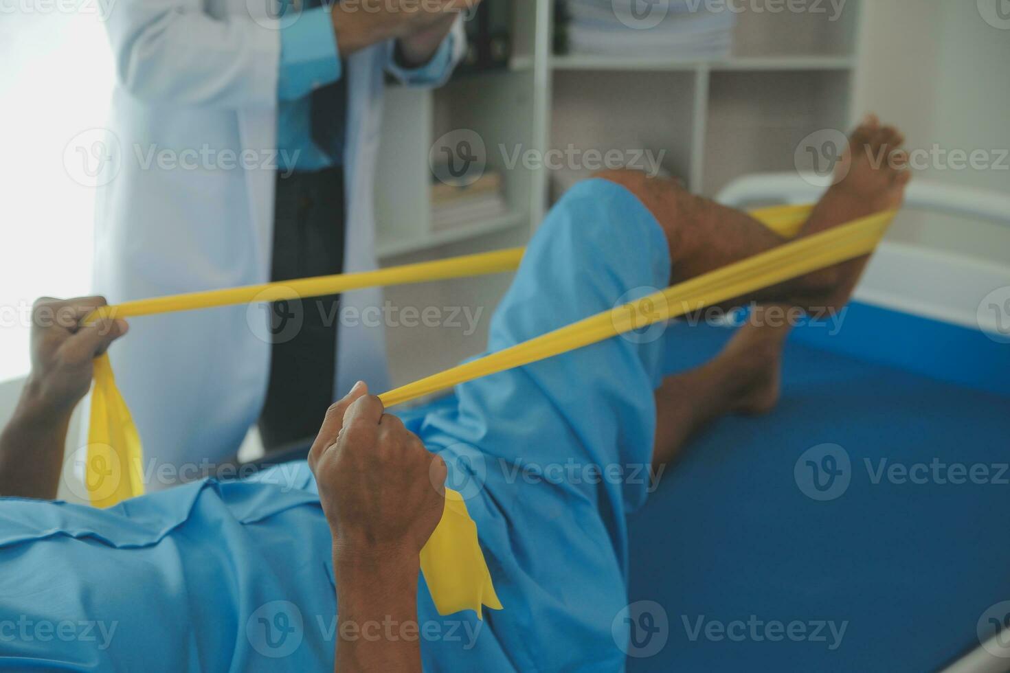 Male patient using elastic band while doing physical exercises for leg muscles at modern clinic, rehabilitation center or hospital. Close up of man's foot. Physiotherapy concept photo