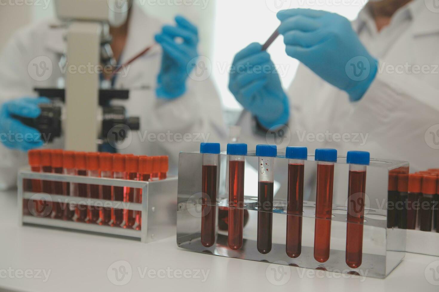 Health care researchers working in life science laboratory. Young female research scientist and senior male supervisor preparing and analyzing microscope slides in research lab. photo
