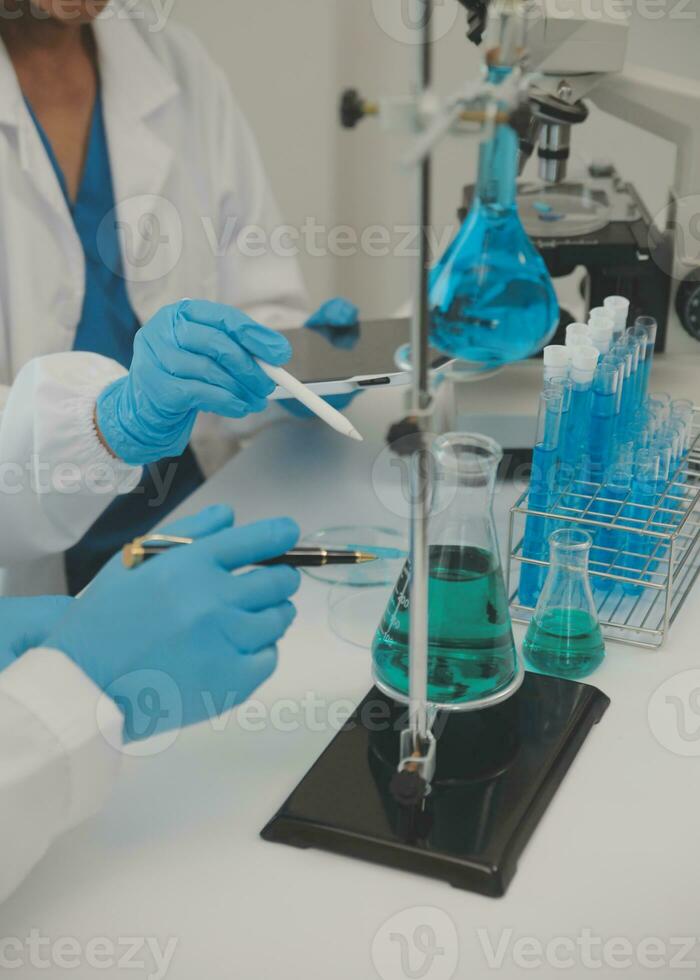 Health care researchers working in life science laboratory. Young female research scientist and senior male supervisor preparing and analyzing microscope slides in research lab. photo