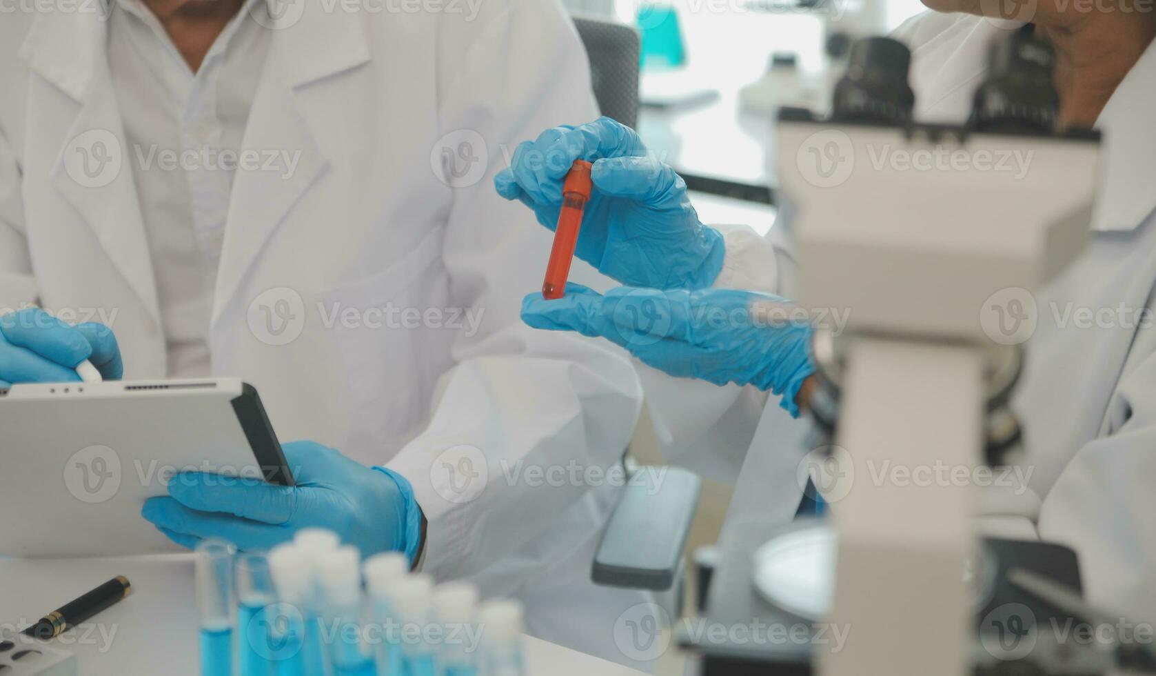Health care researchers working in life science laboratory. Young female research scientist and senior male supervisor preparing and analyzing microscope slides in research lab. photo
