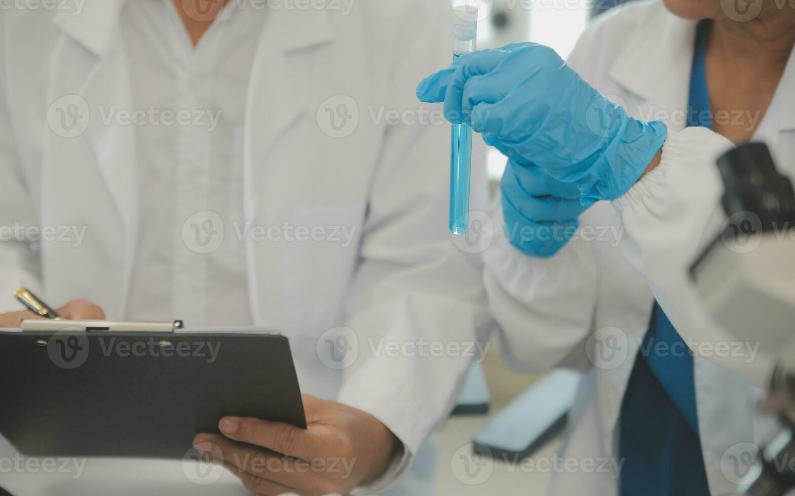 Health care researchers working in life science laboratory. Young female research scientist and senior male supervisor preparing and analyzing microscope slides in research lab. photo