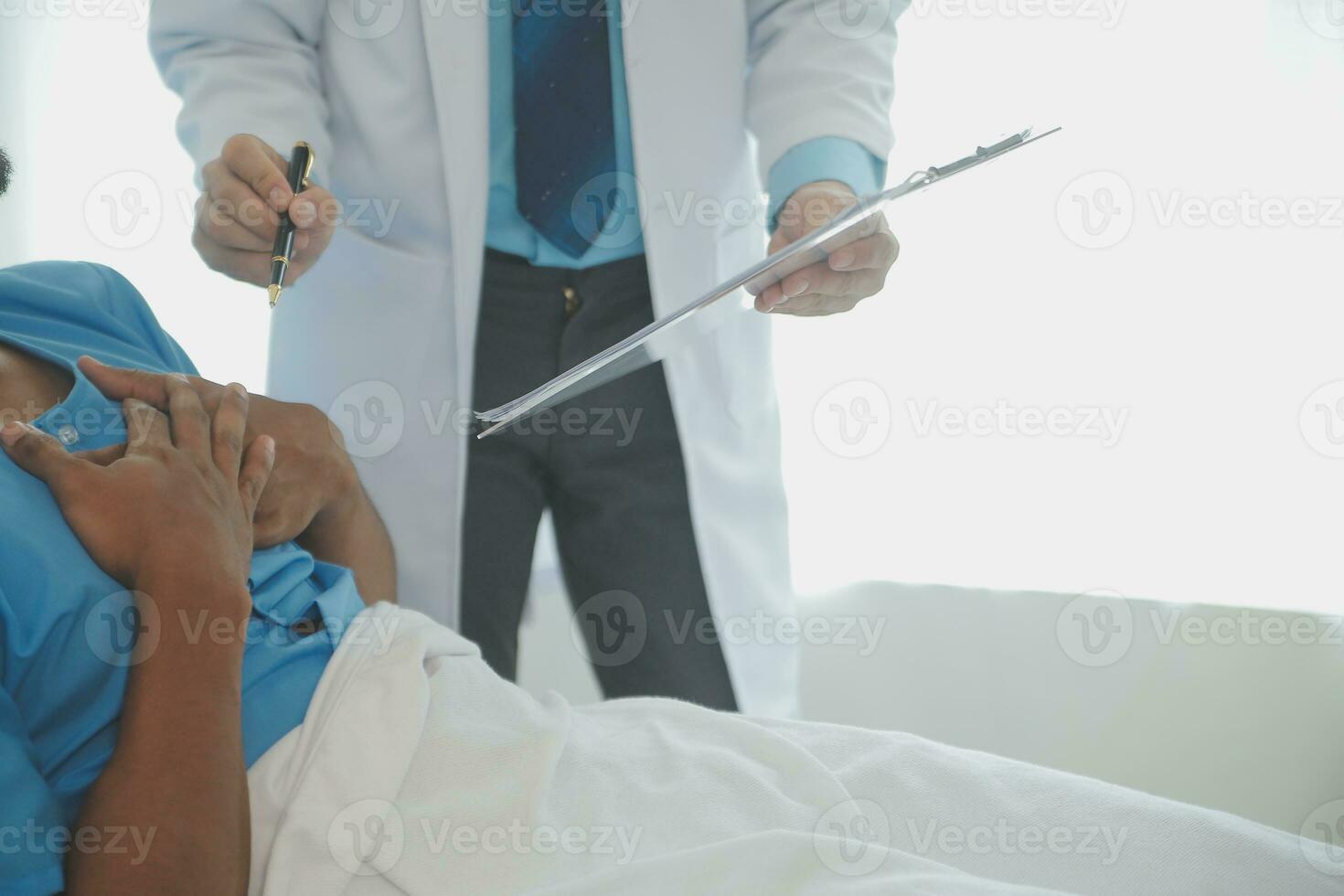 Close up of doctor sitting on bedside of male patient in hospital photo