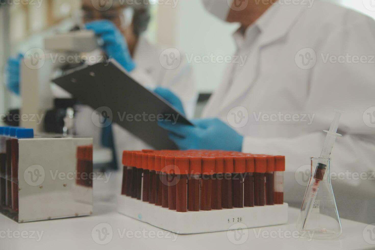 Health care researchers working in life science laboratory. Young female research scientist and senior male supervisor preparing and analyzing microscope slides in research lab. photo