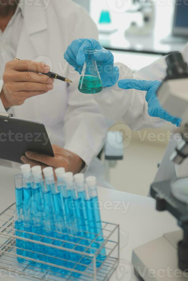 Health care researchers working in life science laboratory. Young female research scientist and senior male supervisor preparing and analyzing microscope slides in research lab. photo