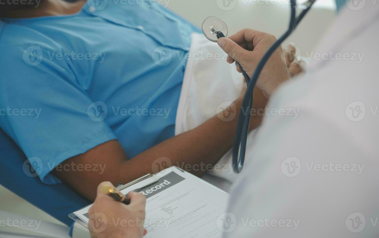 Close up of doctor sitting on bedside of male patient in hospital photo