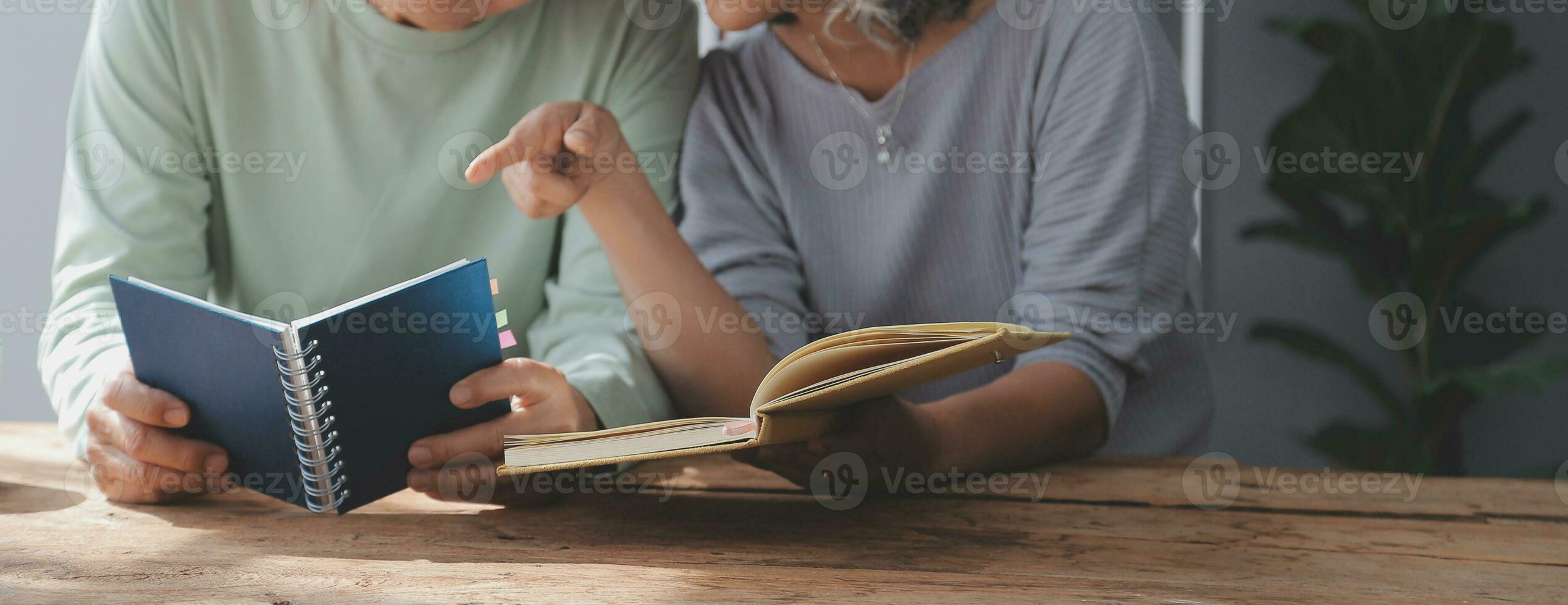 senior asian couple sitting on couch reading a book together photo