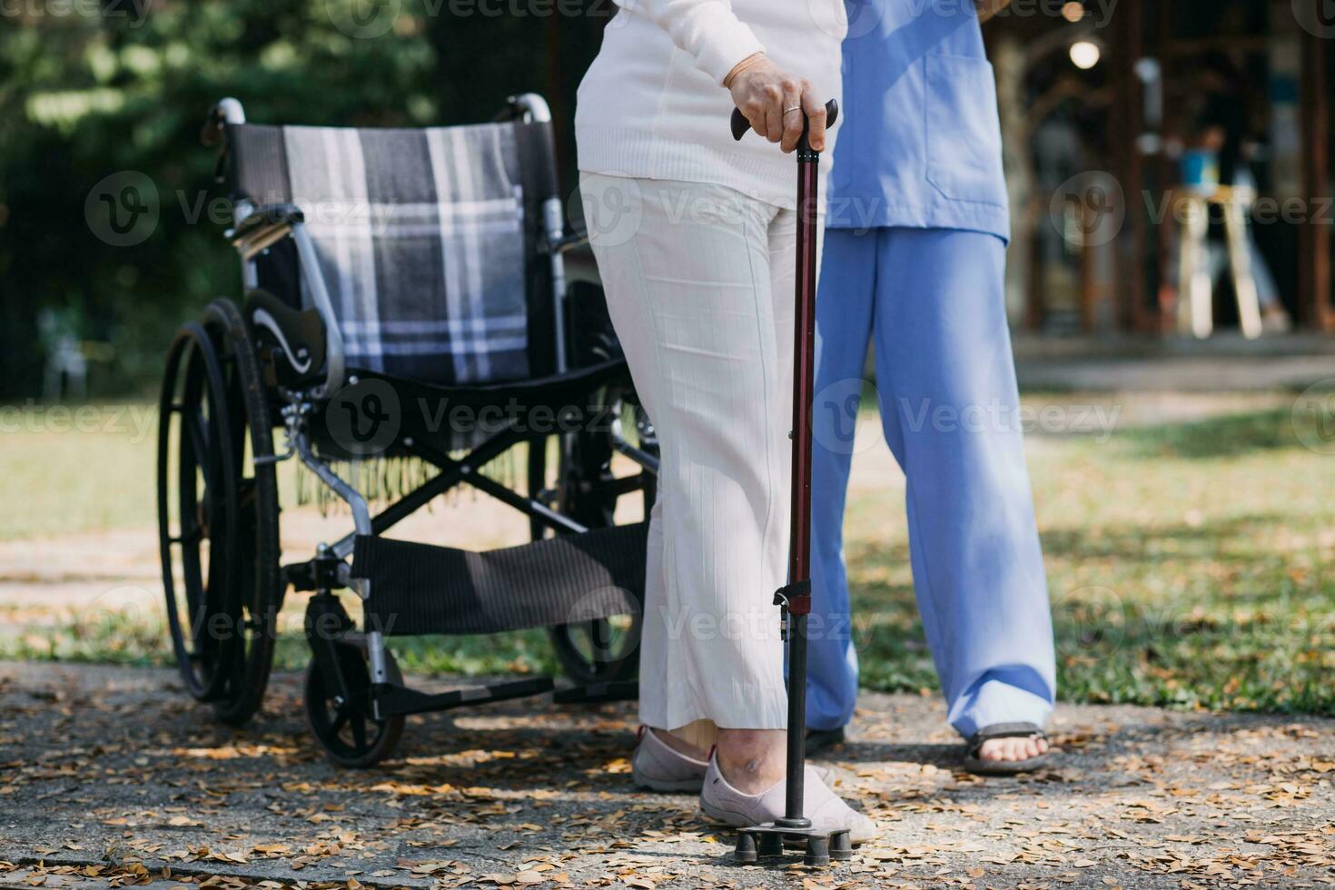 Asian young woman nurse at nursing home take care disabled senior man. Caregiver doctor serve physical therapy for older elderly patient to exercise and practice walking on walker or cane at backyard. photo