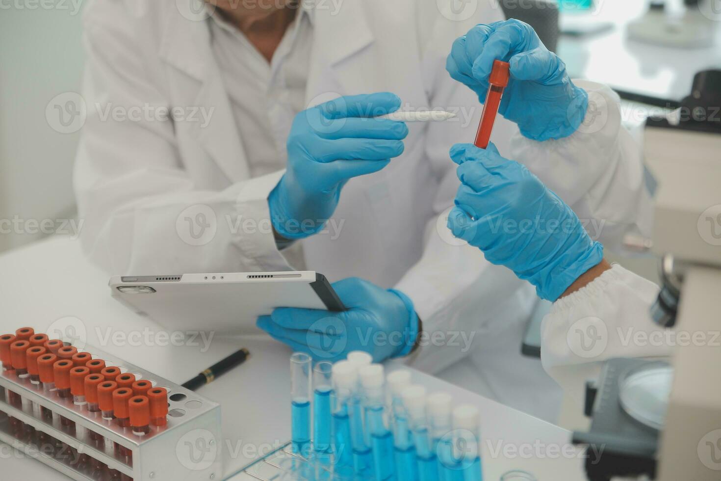 Health care researchers working in life science laboratory. Young female research scientist and senior male supervisor preparing and analyzing microscope slides in research lab. photo