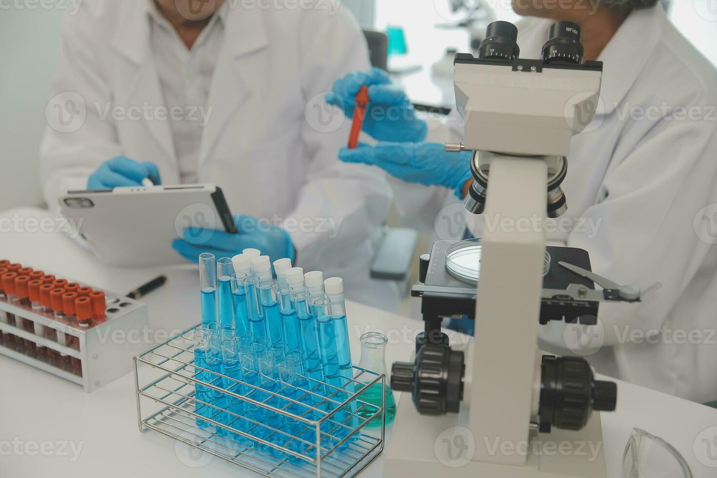Health care researchers working in life science laboratory. Young female research scientist and senior male supervisor preparing and analyzing microscope slides in research lab. photo
