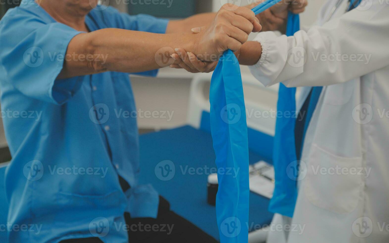 Asian older aged man doing physiotherapist with support from nurse. Senior elderly male sitting on sofa in living room using dumbbells workout exercise for patient with caregiver in nursing care. photo