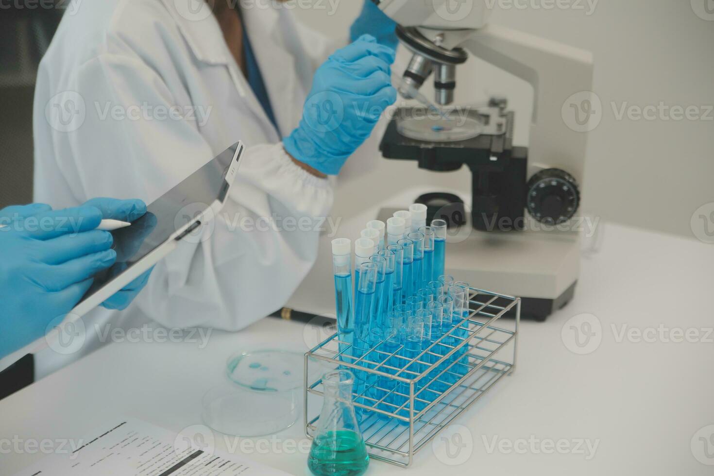 Health care researchers working in life science laboratory. Young female research scientist and senior male supervisor preparing and analyzing microscope slides in research lab. photo