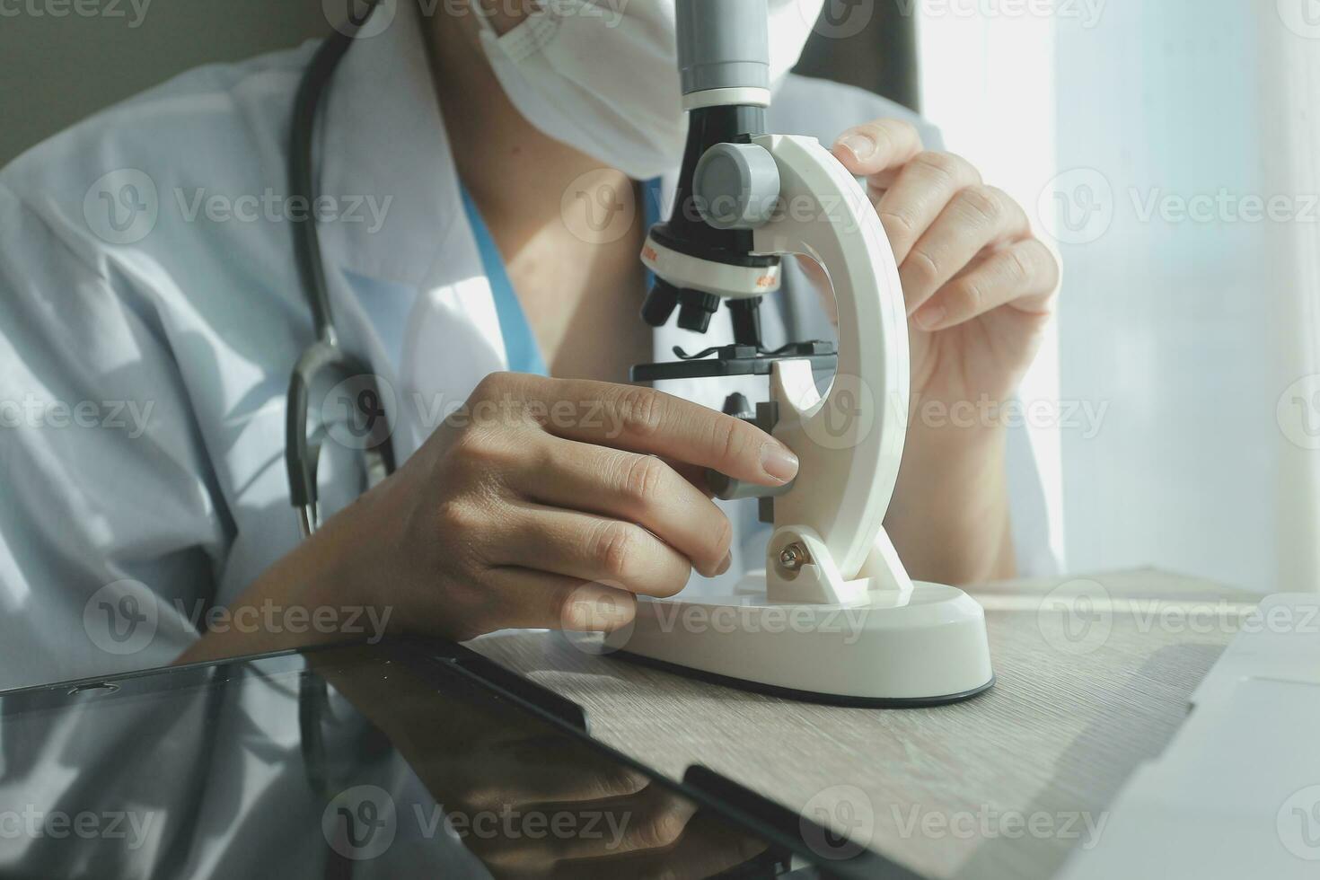 Young scientists conducting research investigations in a medical laboratory, a researcher in the foreground is using a microscope photo