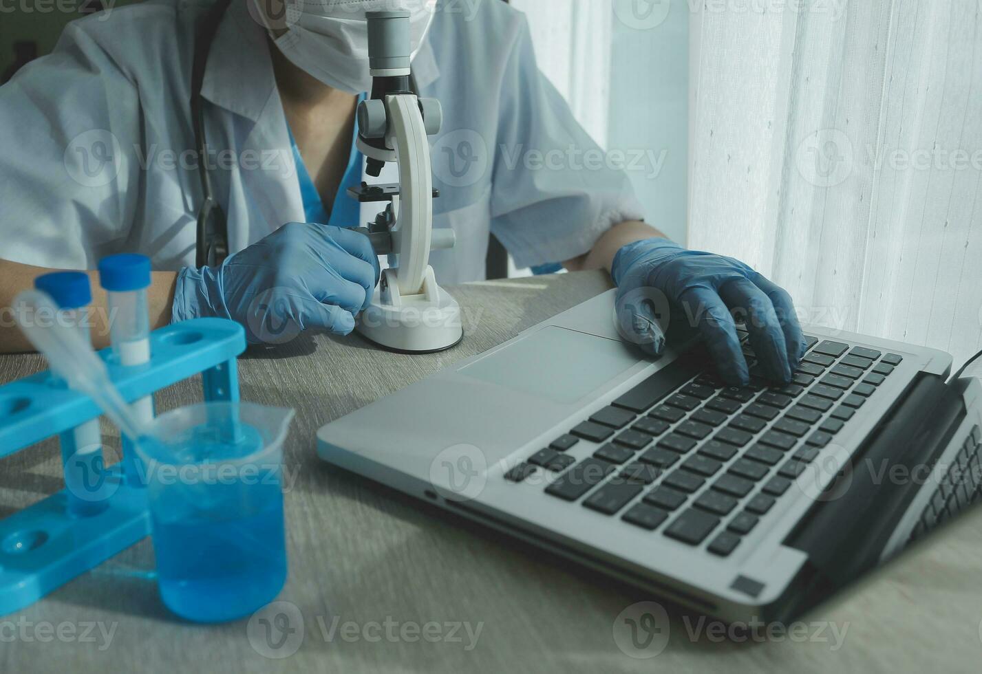 Young scientists conducting research investigations in a medical laboratory, a researcher in the foreground is using a microscope photo