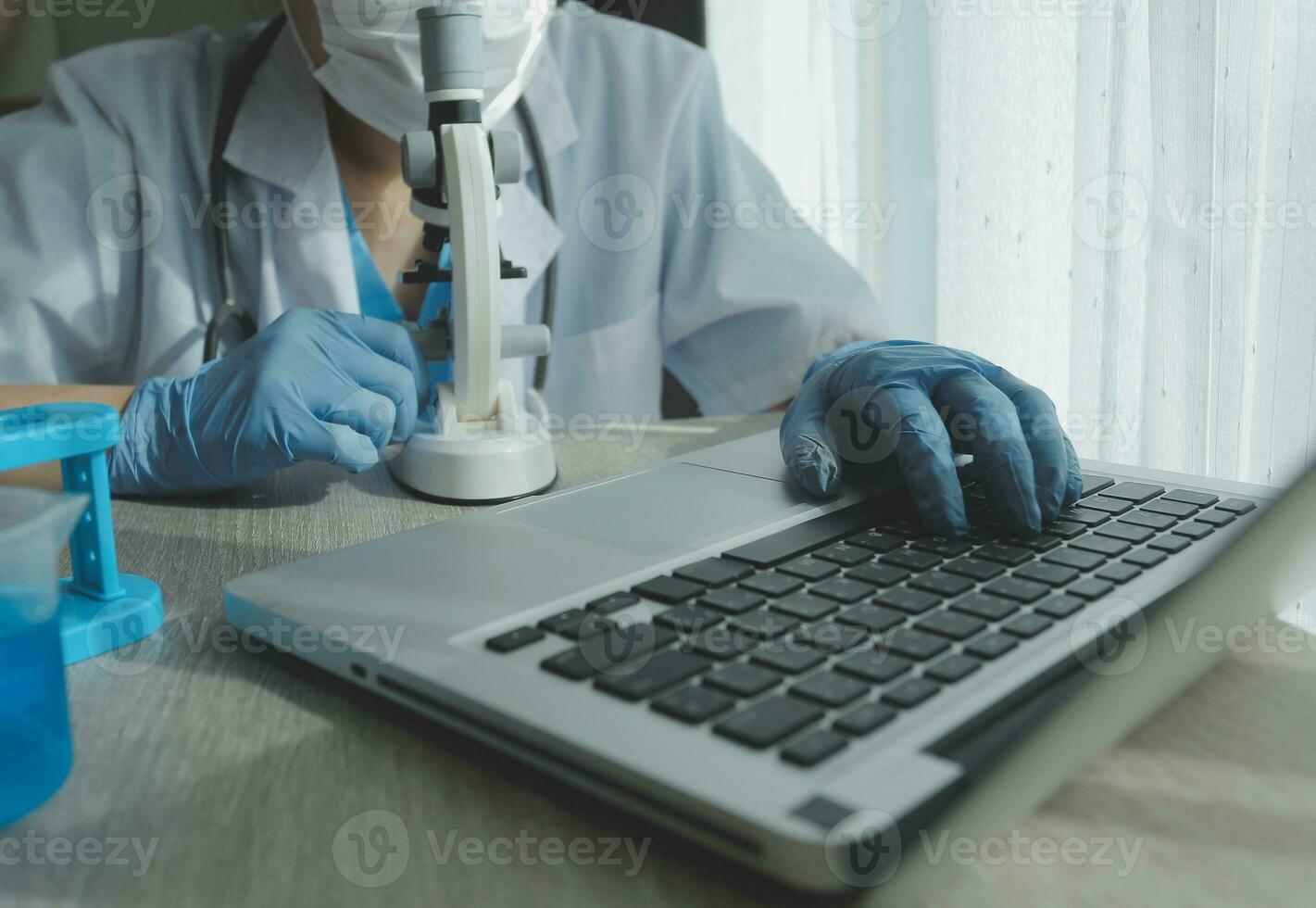 Young scientists conducting research investigations in a medical laboratory, a researcher in the foreground is using a microscope photo