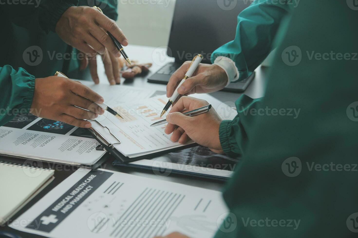 Multiracial team of doctors discussing a patient standing grouped in the foyer looking at a tablet computer, close up view photo