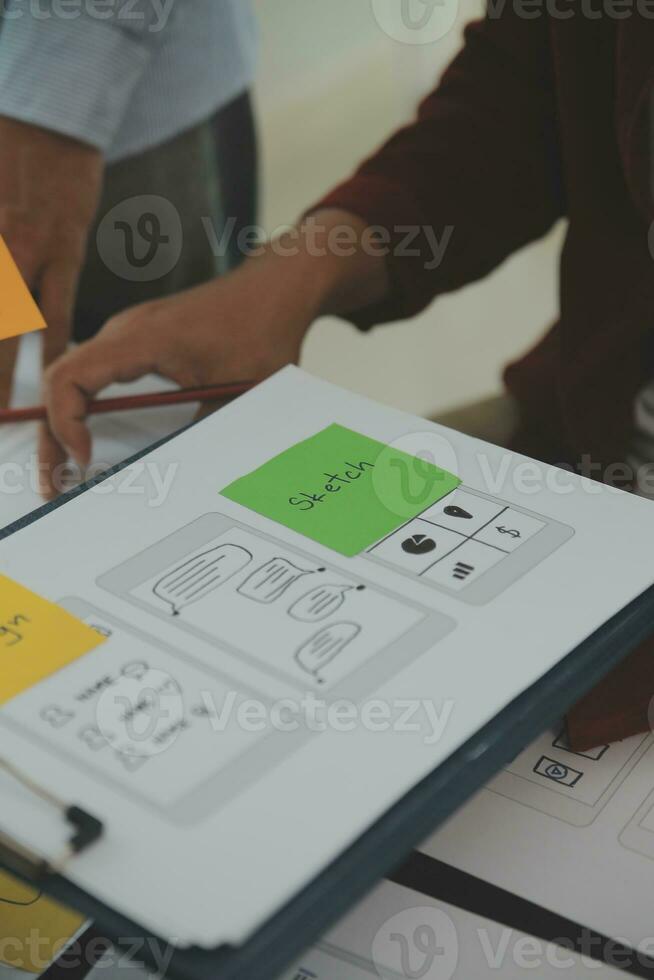 Close up ux developer and ui designer brainstorming about mobile app interface wireframe design on table with customer breif and color code at modern office.Creative digital development agency photo
