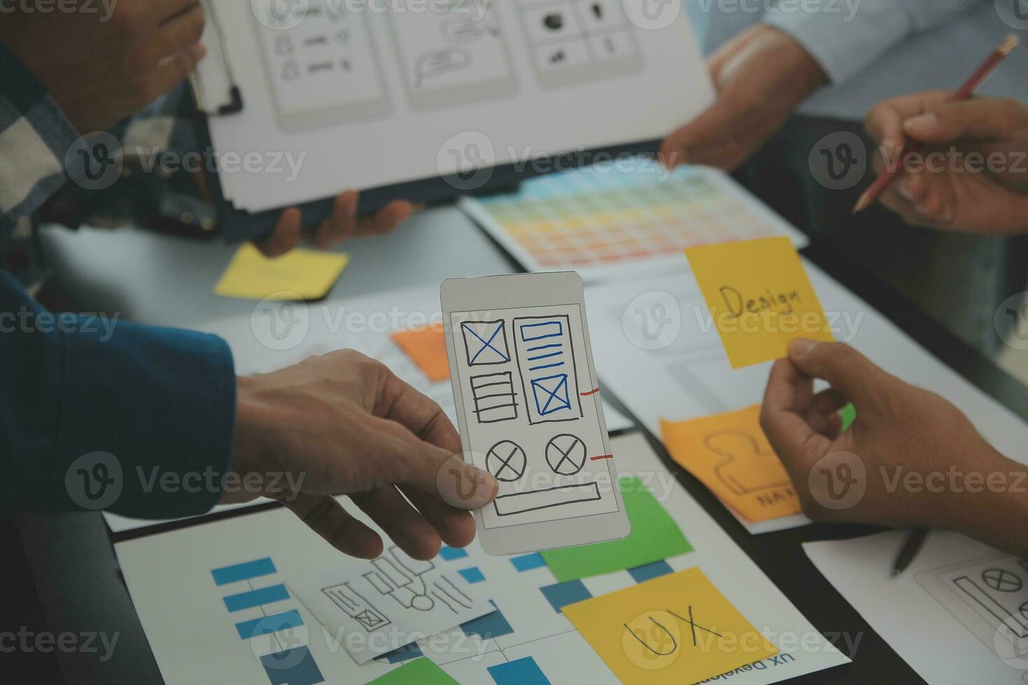 Close up ux developer and ui designer brainstorming about mobile app interface wireframe design on table with customer breif and color code at modern office.Creative digital development agency photo