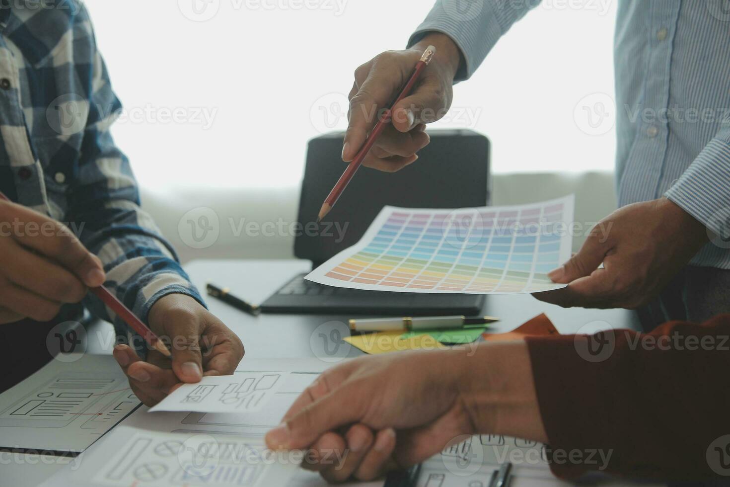 Close up ux developer and ui designer brainstorming about mobile app interface wireframe design on table with customer breif and color code at modern office.Creative digital development agency photo