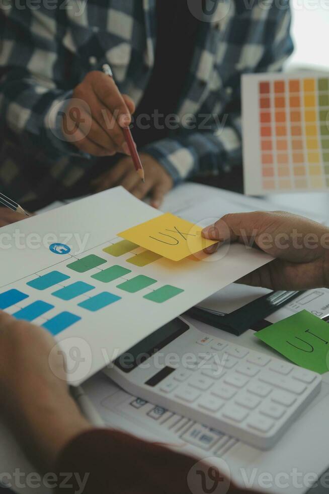 Close up ux developer and ui designer brainstorming about mobile app interface wireframe design on table with customer breif and color code at modern office.Creative digital development agency photo