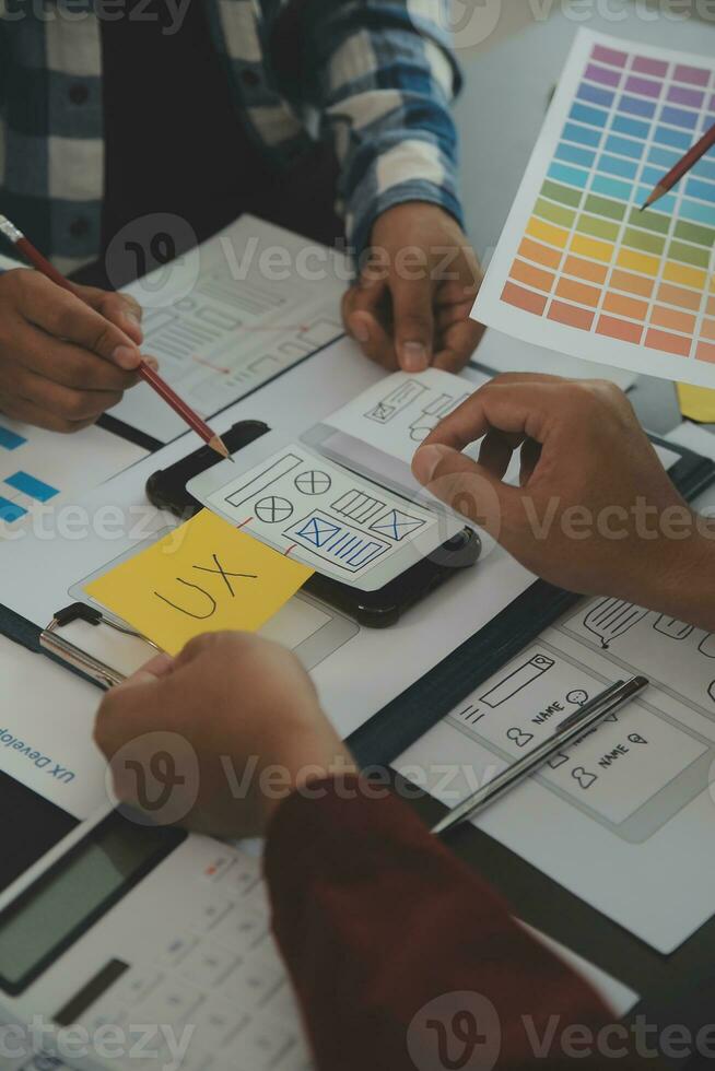 Close up ux developer and ui designer brainstorming about mobile app interface wireframe design on table with customer breif and color code at modern office.Creative digital development agency photo
