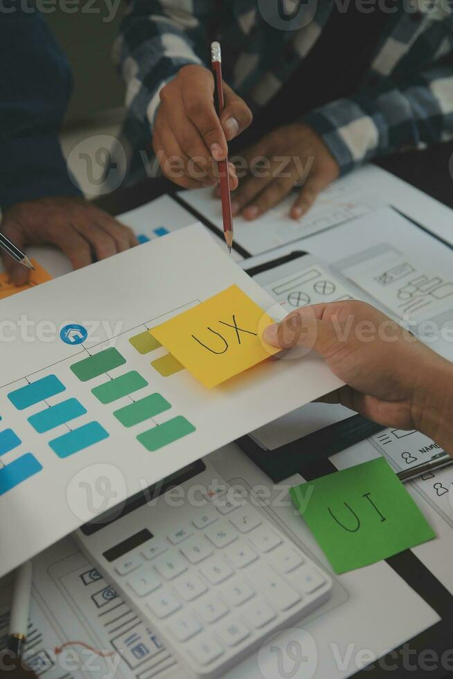 Close up ux developer and ui designer brainstorming about mobile app interface wireframe design on table with customer breif and color code at modern office.Creative digital development agency photo