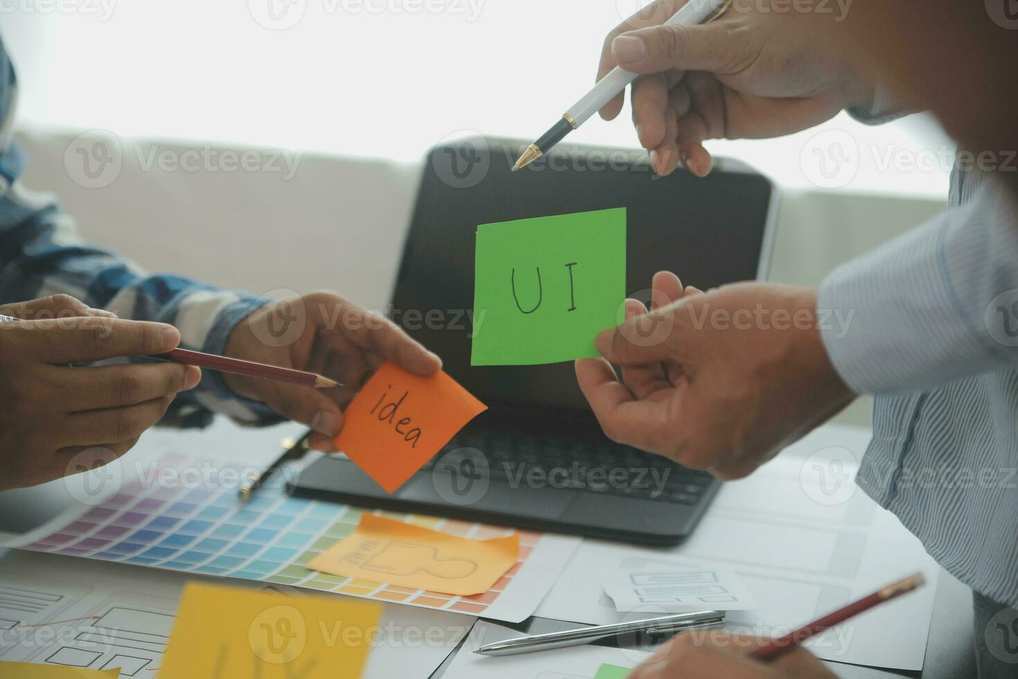 Close up ux developer and ui designer brainstorming about mobile app interface wireframe design on table with customer breif and color code at modern office.Creative digital development agency photo