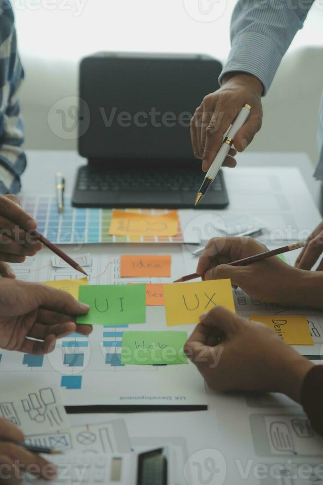 Close up ux developer and ui designer brainstorming about mobile app interface wireframe design on table with customer breif and color code at modern office.Creative digital development agency photo