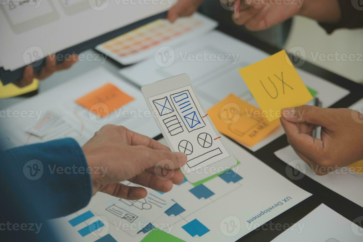 Close up ux developer and ui designer brainstorming about mobile app interface wireframe design on table with customer breif and color code at modern office.Creative digital development agency photo