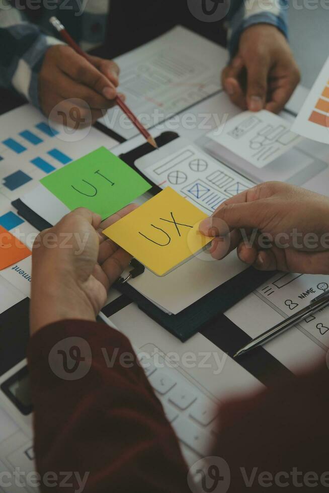 Close up ux developer and ui designer brainstorming about mobile app interface wireframe design on table with customer breif and color code at modern office.Creative digital development agency photo