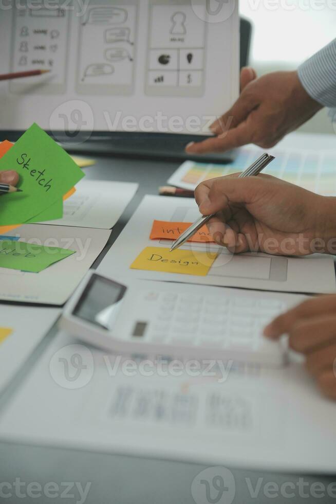 Close up ux developer and ui designer brainstorming about mobile app interface wireframe design on table with customer breif and color code at modern office.Creative digital development agency photo