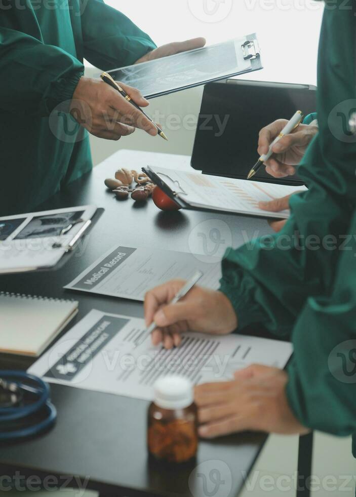 Multiracial team of doctors discussing a patient standing grouped in the foyer looking at a tablet computer, close up view photo