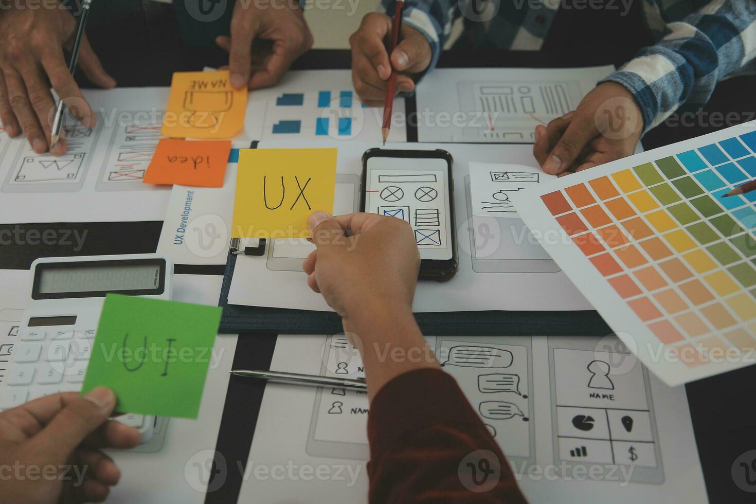 Close up ux developer and ui designer brainstorming about mobile app interface wireframe design on table with customer breif and color code at modern office.Creative digital development agency photo