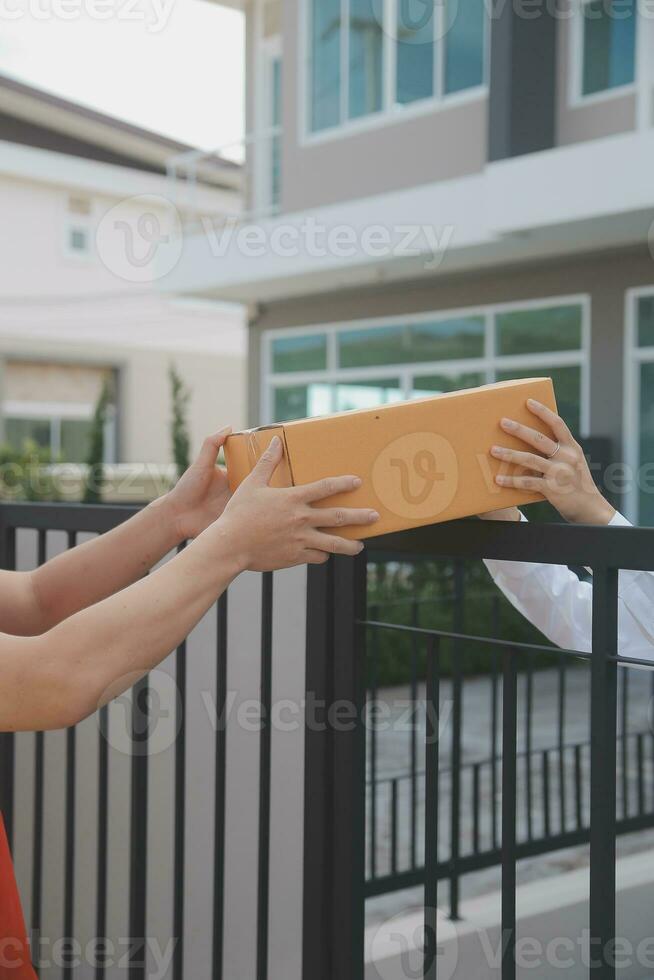 Asian Woman Receiving Product from delivery man at Home, Young Owner Woman Order Product from Smartphone Application, Woman with Online Business or SME Concept. photo