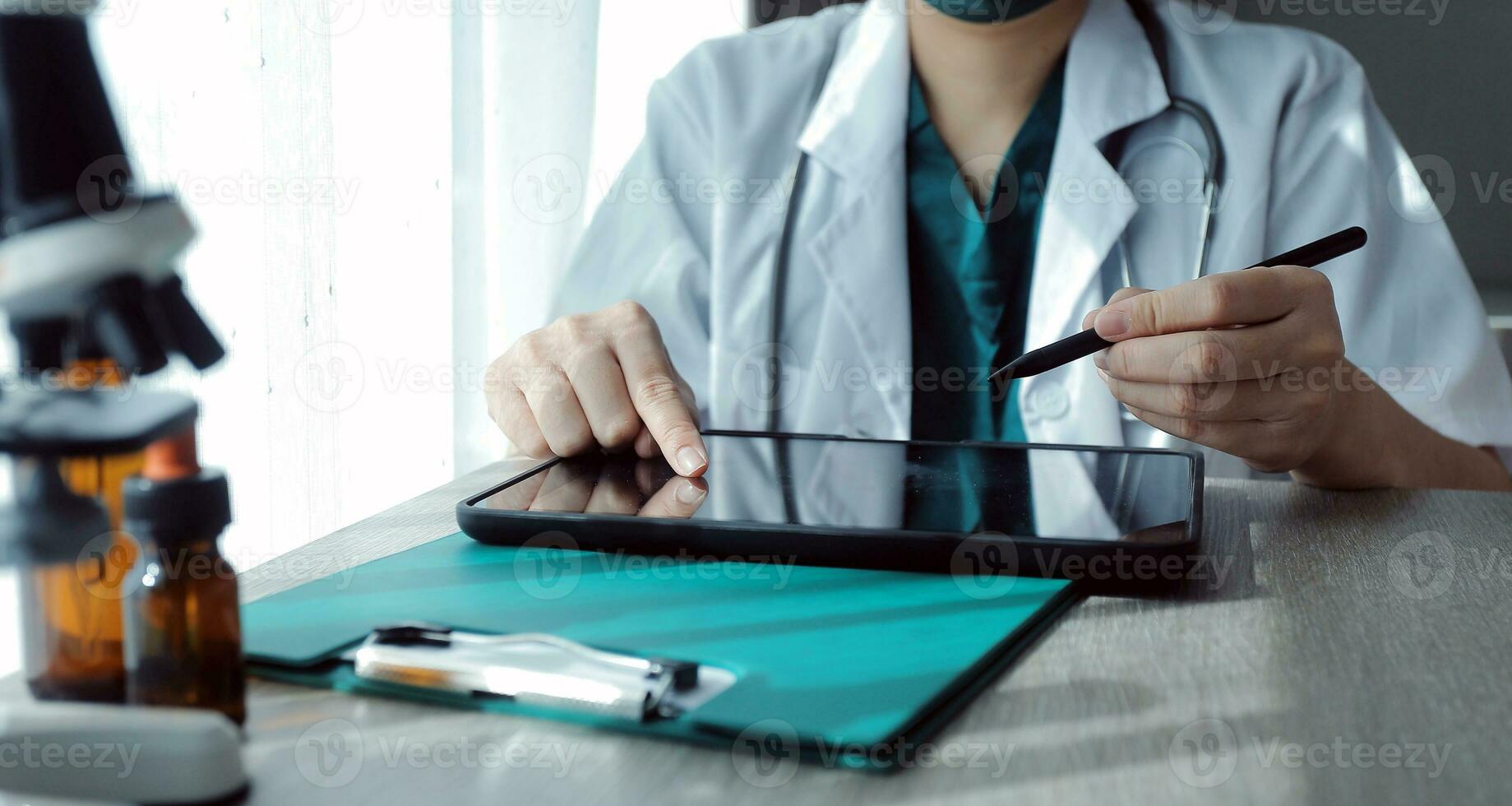 Research and experiments in the pharmaceutical or chemical industry. Female scientist in lab or chemist making notes on laptop by studying liquid in test tube. Scientists working on the background. photo