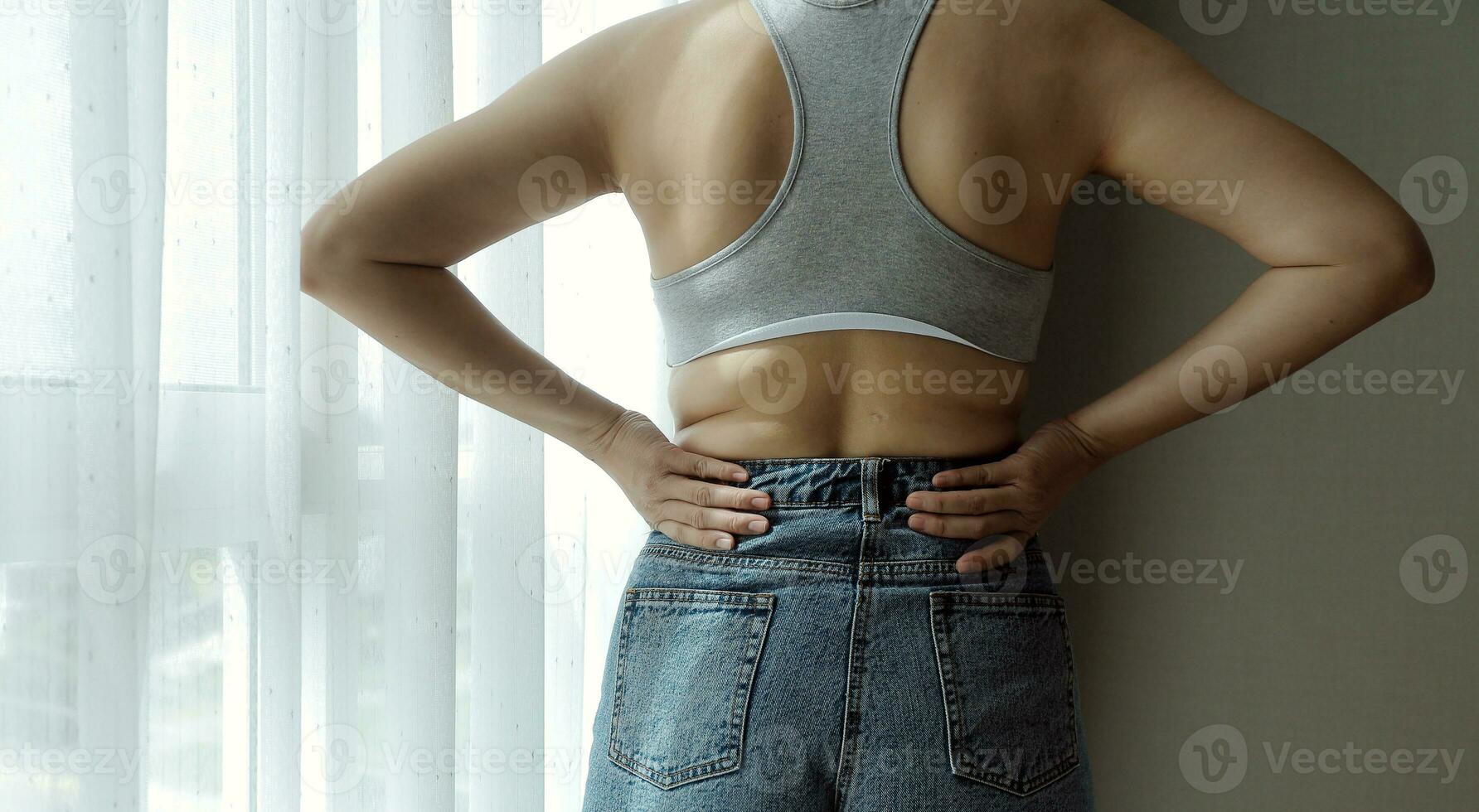 Close up of a belly with scar from c-section and abdominal fat. Women's health. A woman dressed up in sportswear demonstrating her imperfect body after a childbirth with nursery on the background. photo