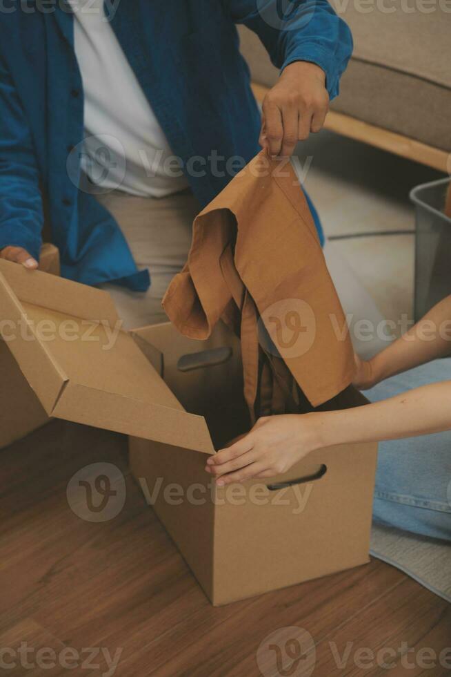 Beautiful young couple in love having fun unpacking things from cardboard boxes while moving in together in their new apartment photo