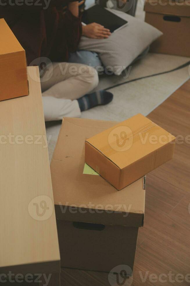 Beautiful young couple in love having fun unpacking things from cardboard boxes while moving in together in their new apartment photo