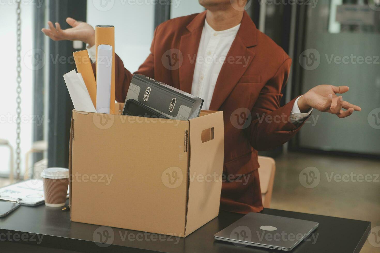 Business man employee stressful resignation from job while picking up personal belongings into brown cardboard box and carrying to walking out from office photo